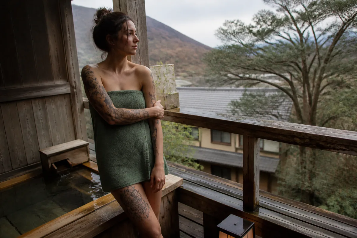Voyageuse tatouée devant un bain extérieur privatif dans un ryokan japonais